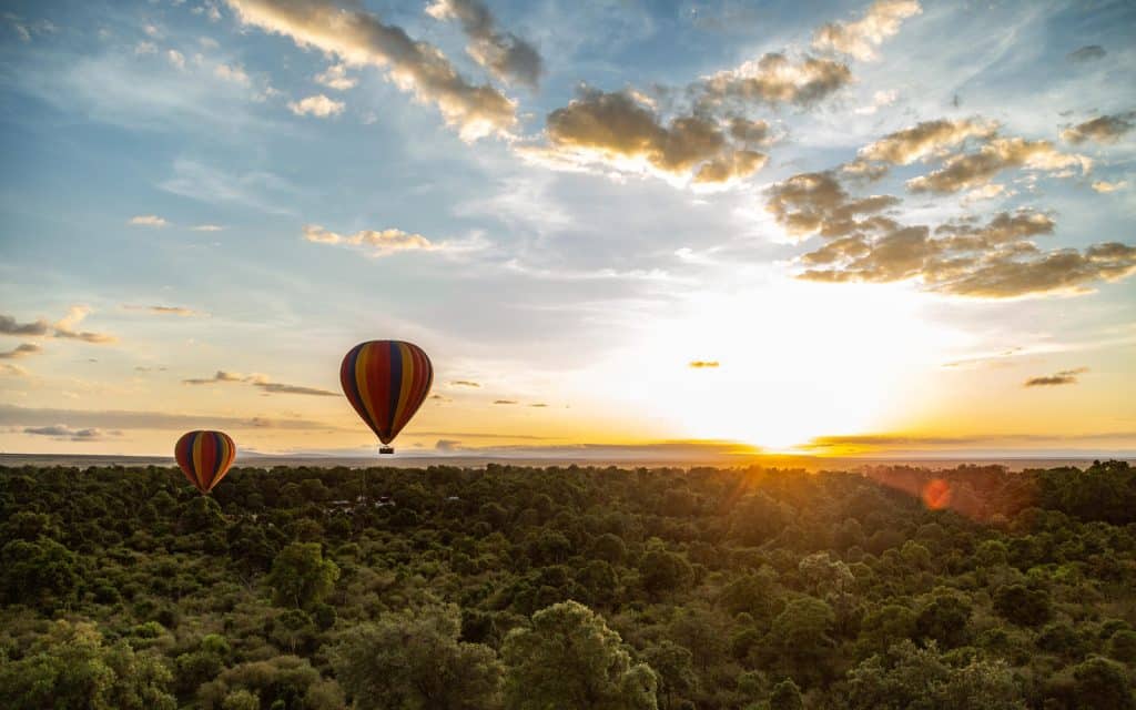 A hot air balloon at sunrise over the Mara Triangle below Angama Mara